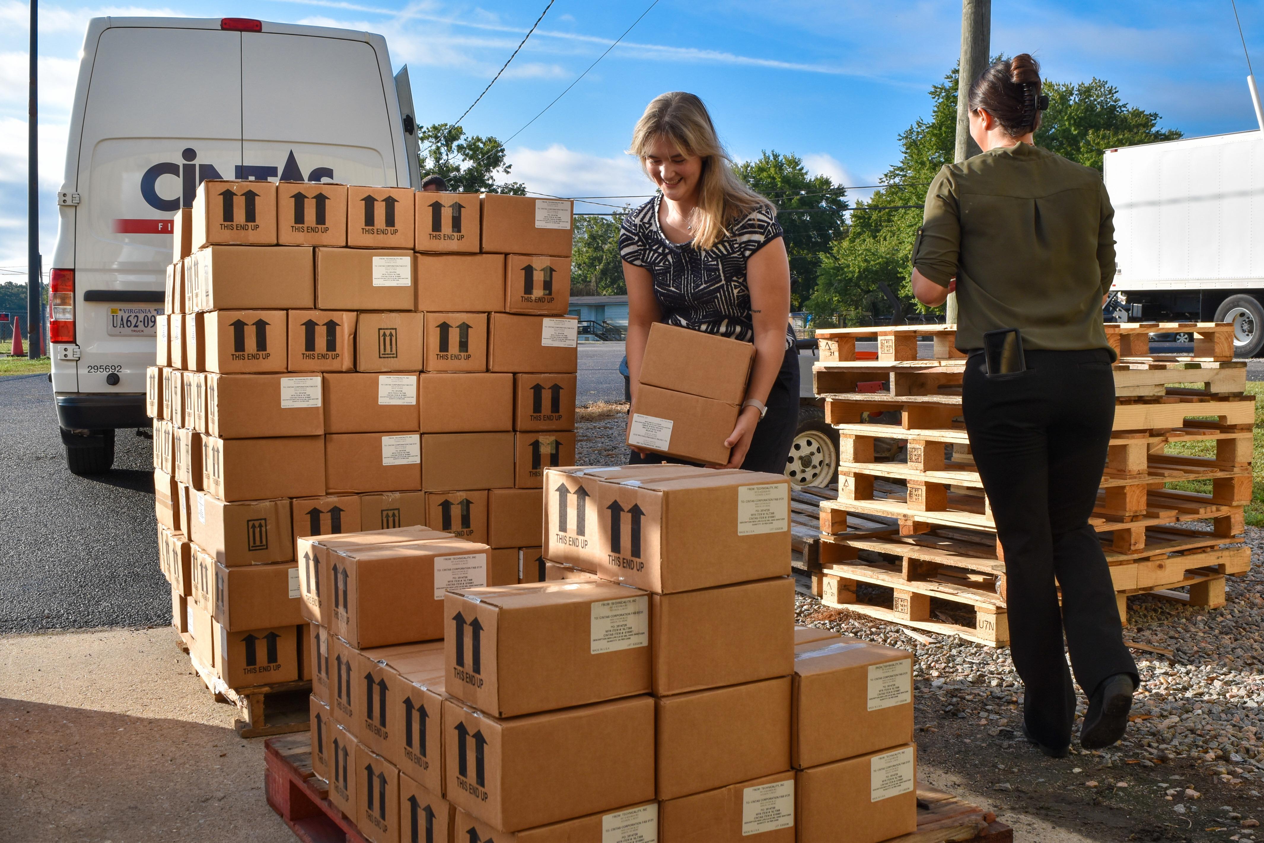 Cintas staff loads boxes of hand sanitizer onto pallets as they deliver the donation to the division's central ware